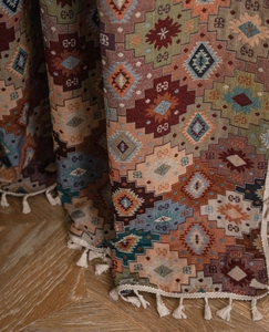 Close-up of geometric jacquard woven fabric with bohemian patterns and white tassels