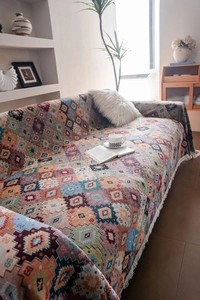 Close-up of bohemian geometric jacquard sofa cover with white decorative tassels