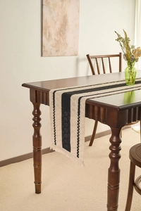 Detail of minimalist black and white striped table runner with fringes on wood table