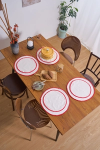 Set of 4 white round linen placemats with red wavy edges on a wooden dining table