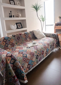 Detail of bohemian sofa cover featuring colorful geometric patterns and white fringe edges