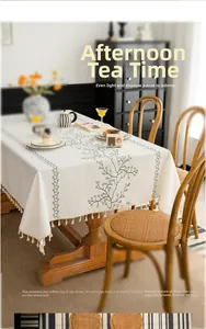 Close-up of linen-style tablecloth with floral embroidery and elegant hanging tassels