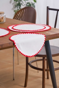 Detail of white cotton linen placemats and table runner with red scalloped edge embroidery