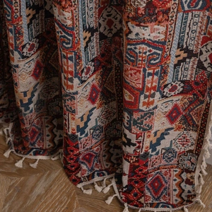 Tenda jacquard bohémien con motivi geometrici colorati e nappe eleganti sul pavimento