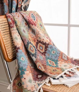 Close-up of bohemian knitted throw with geometric ethnic patterns and white tassels