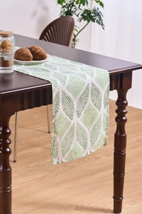 Close-up of green and white geometric jacquard table runner on a wooden dining table