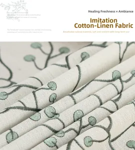 Close-up of linen-style fabric featuring green vine embroidery and soft texture
