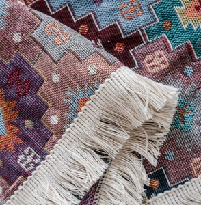 Detail of bohemian geometric jacquard sofa cover with thick knit texture and white tassels
