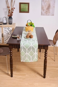 Detailed close-up of a Nordic table runner with green leaf patterns on a wooden dining table