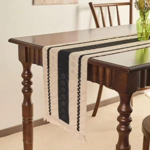 Modern black and white striped table runner with fringes on a rustic wooden table