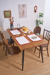 Detailed view of white cotton linen placemats with red scalloped crochet edges on a wooden table