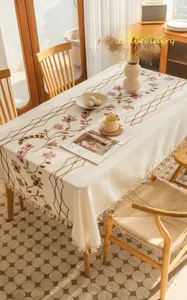 Close-up of floral embroidery detail and fringe edges on beige linen tablecloth