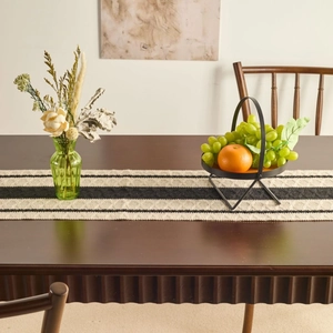 Modern minimalist black and white striped table runner with woven wavy edges on wood table