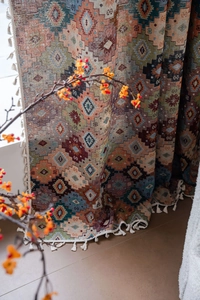 Detailed close-up of bohemian geometric jacquard curtain fabric with white cotton tassels