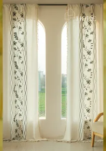 Detail of floral embroidery and beige tassel trim on semi-sheer linen curtains