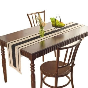 Modern minimalist black and white striped table runner with fringed edges on wooden table