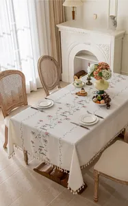Detail of cream floral embroidered tablecloth with elegant fringe trim on edges