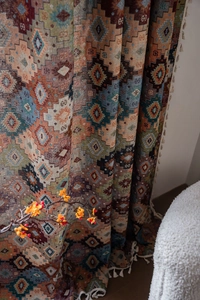 Detail of geometric diamond jacquard curtain fabric with white fringe tassels