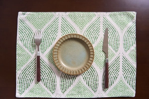 Close-up of ceramic plate and stainless steel cutlery on geometric jacquard table runner