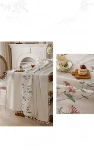 Detail of floral embroidery and beige tassels on a cotton cream table runner