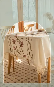 Detail of floral embroidery and fringe tassels on a cream cotton tablecloth