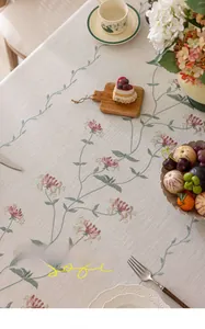 Detail of cream tablecloth featuring floral embroidery and elegant tassels on a cotton base