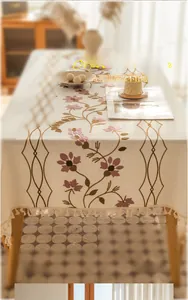 Detail of floral embroidery and fringe edge on a rectangular linen-like tablecloth