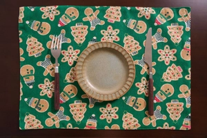 Close-up of green Christmas placemat with gingerbread man and snowflake patterns on wood