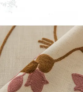 Macro shot of floral embroidery details on beige linen-textured rectangular tablecloth