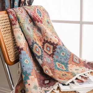 Bohemian geometric jacquard woven blanket with fringe on a rattan chair