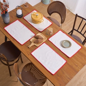Set of 4 white cotton linen placemats with red embroidery on a wooden dining table