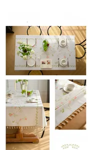 Detailed close-up of pink flower embroidery and white tassels on cotton linen tablecloth