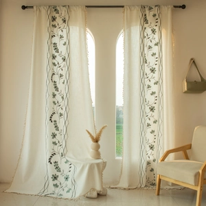 Detail of floral embroidery and beige tassel fringes on linen blend curtains