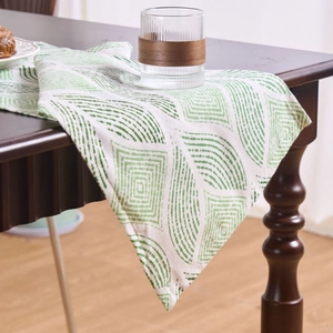 Nordic geometric jacquard table runner with green leaf patterns and tassels on wood table