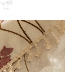Detail of floral embroidery and hanging tassel edge on beige cotton linen tablecloth