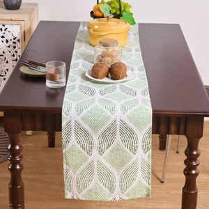Nordic table runner with green and white leaf pattern on a dark wooden table