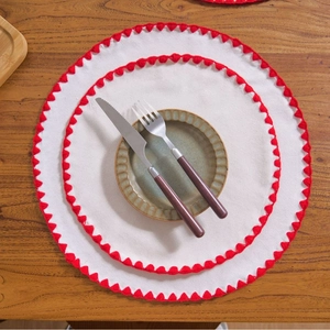 Minimalist round cotton linen placemat with red scalloped embroidery edge on wood table