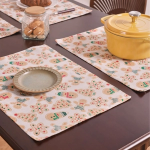 Vintage Christmas placemat featuring gingerbread and tree prints on wooden dining table