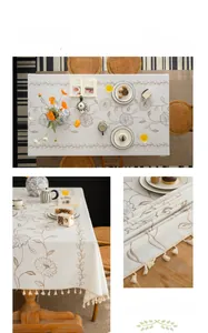 Detail of cream fabric tablecloth with floral embroidery and elegant tassel edges
