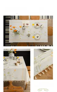 Detail showing intricate pumpkin flower embroidery and white tassels on linen tablecloth