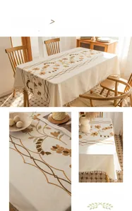 Detail of floral grapevine embroidery and tassel edge on beige linen tablecloth
