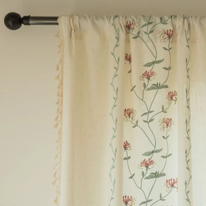 Modern beige linen curtain with floral embroidery and tassel fringe on a rod
