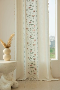 Detail of floral embroidery on beige cotton linen curtain with decorative tassel trim edge