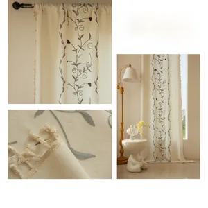 Detail of cream curtain with grey floral embroidery and decorative tassel edges