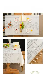 Detail of leaf embroidery and cotton ball tassels on a beige linen tablecloth