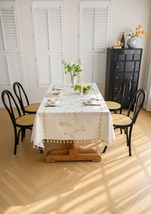 Detailed close-up of pastoral floral embroidery and beige tassel edge on cotton linen tablecloth