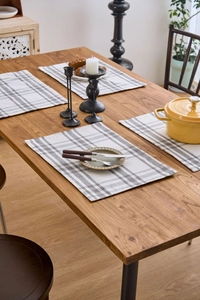 Close-up of gray and beige checkered heat-resistant placemats on a wooden dining table