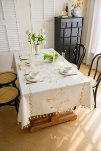 Detail of floral embroidery and tassel fringe on beige cotton linen tablecloth