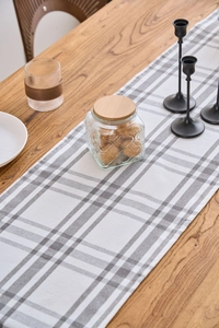 Macro detail of Nordic gray and white plaid table runner on a wooden surface
