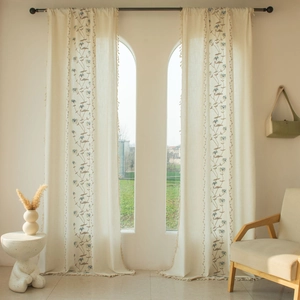 Detail of cream floral embroidered curtain with linen texture and beige fringe tassels